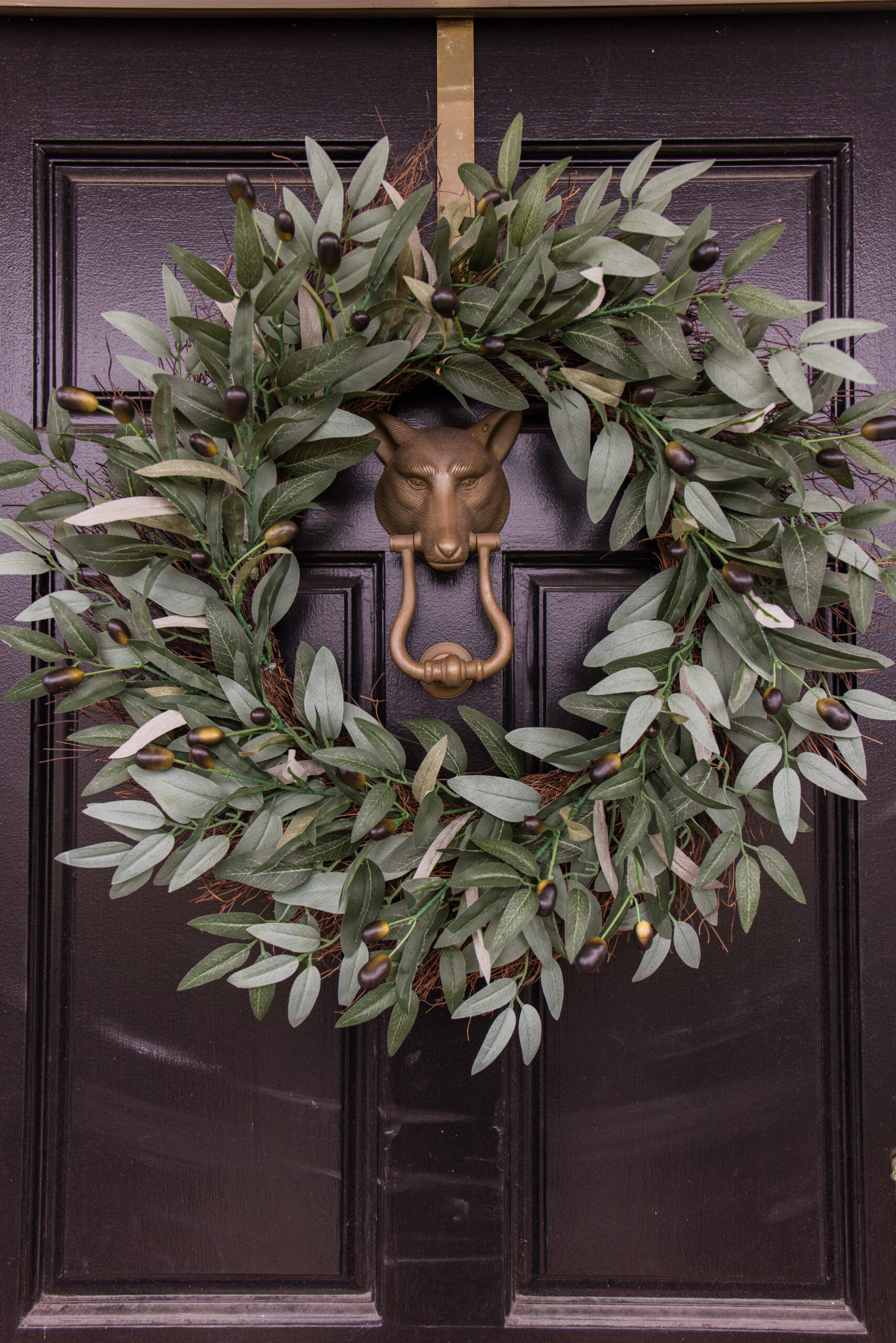 Arched manor spring front door styling, close up image of faux olive wreath on black front door