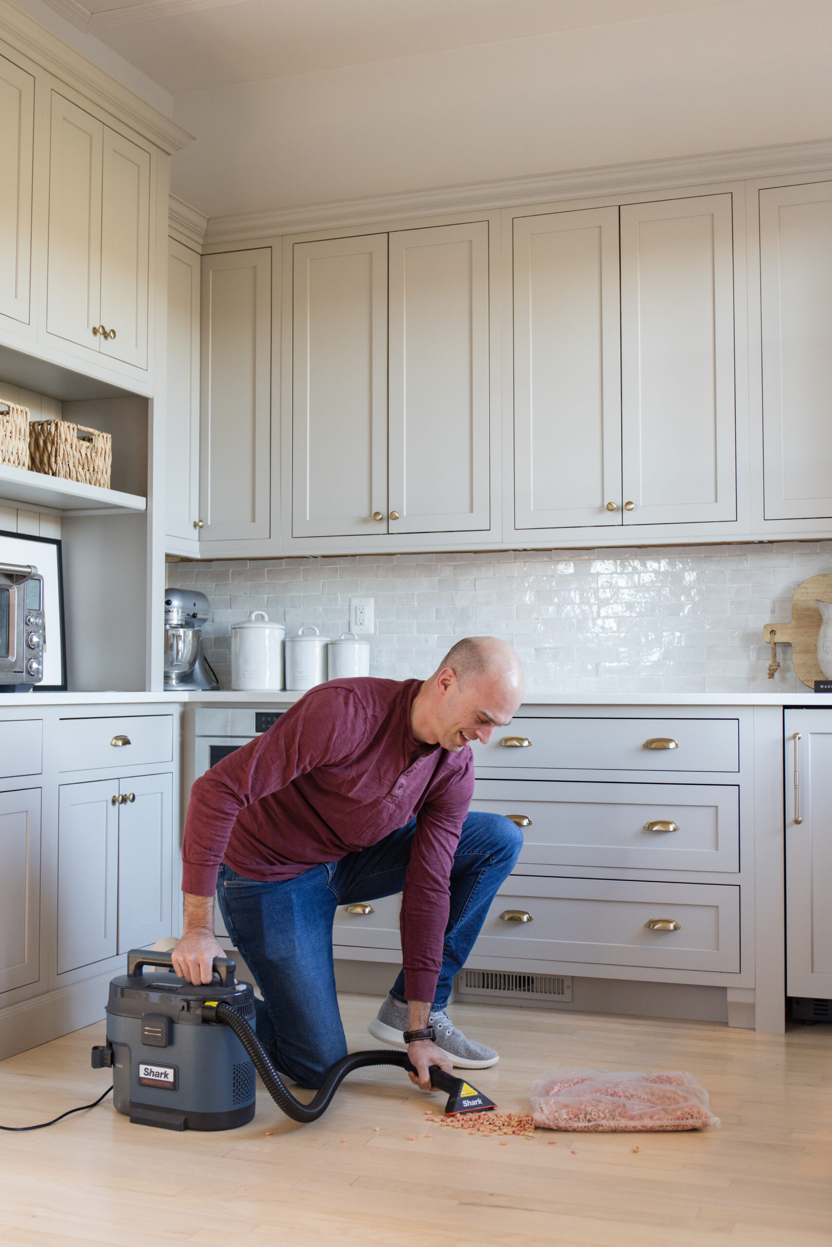 spring cleaning refresh, john using the shark shop vac vacuum to clean spilled cereal on kitchen floor