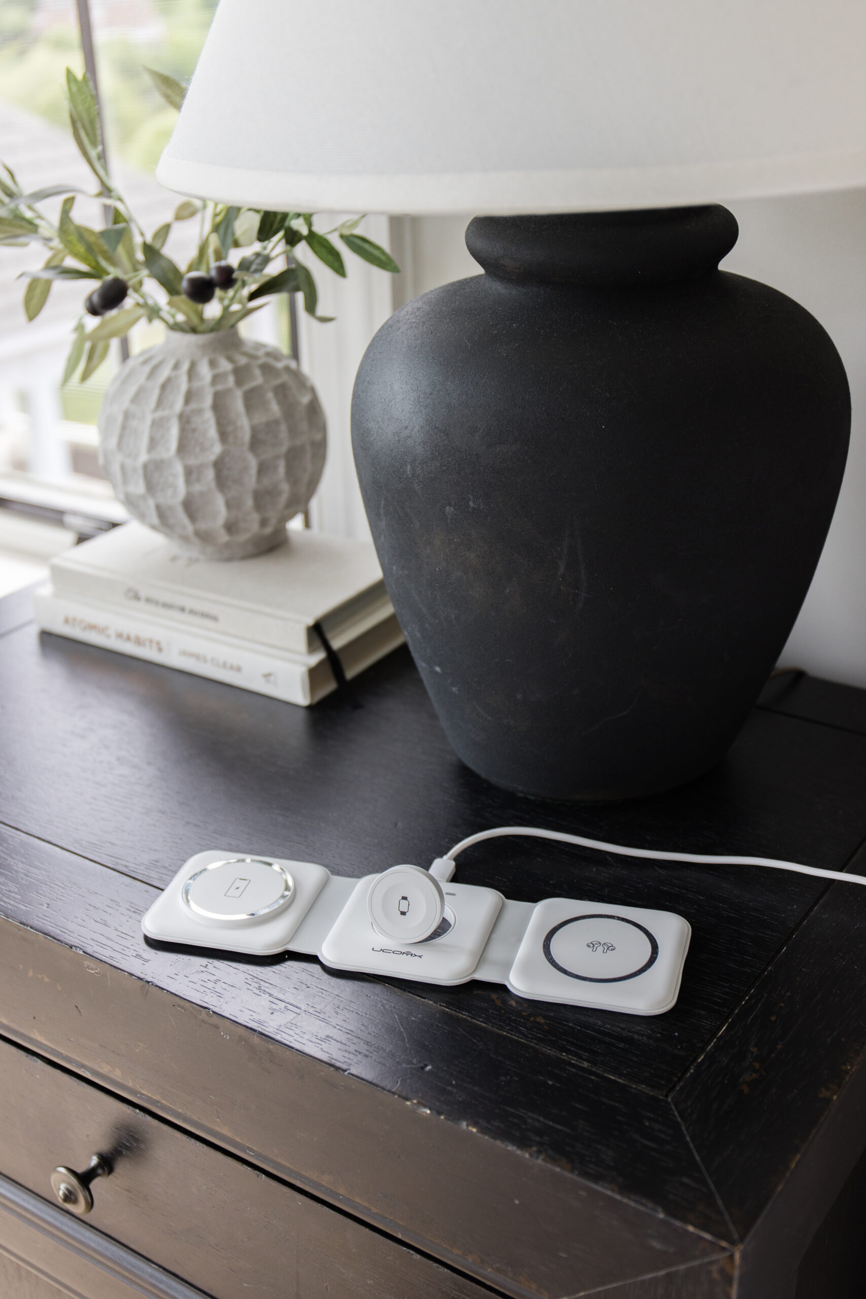 3-in-1 Charging Station next to black lamp on nightstand with white vase filled with faux stems.